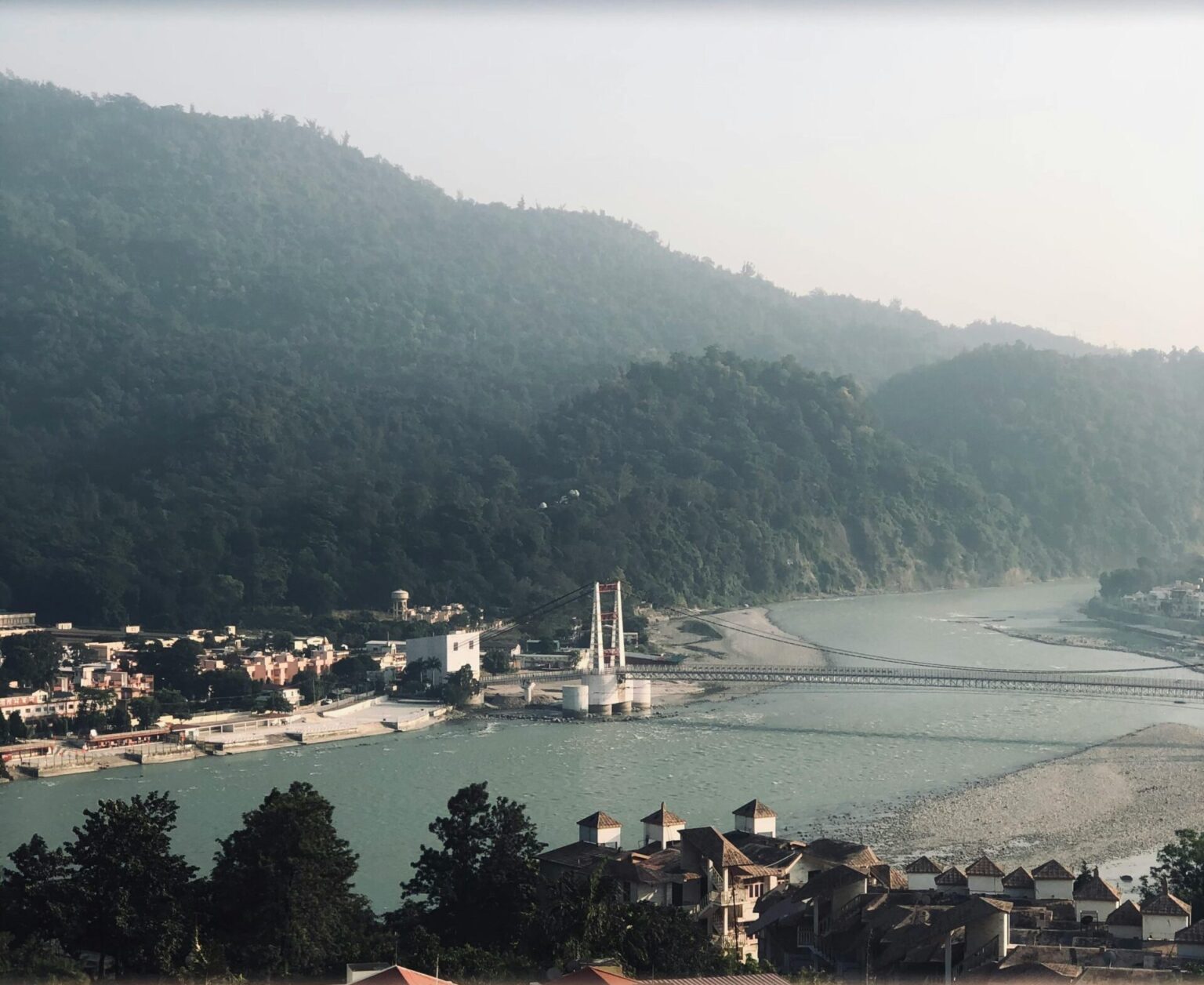 A tranquil view of Rishikesh with the Ganges River and mountains in the background, capturing the peaceful essence of this town.